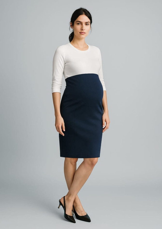 A maternity skirt in navy blue, paired with a white top, worn by a pregnant woman in a studio setting.