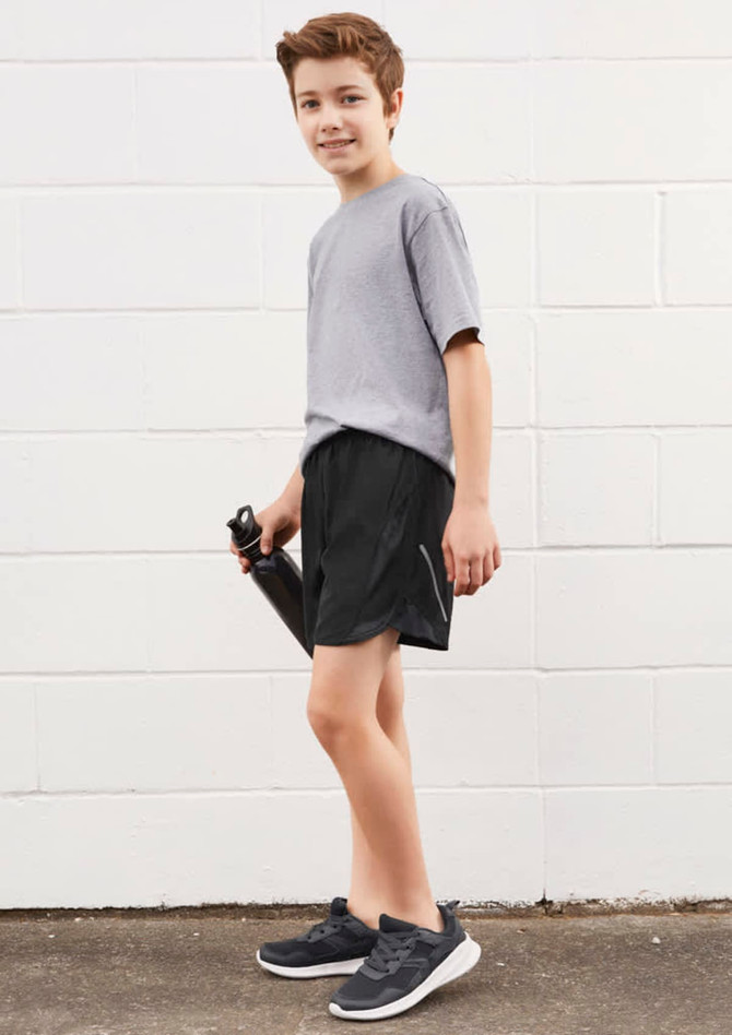 A boy is wearing grey sports shorts and a grey t-shirt, holding a drink bottle. The shorts are black in colour.