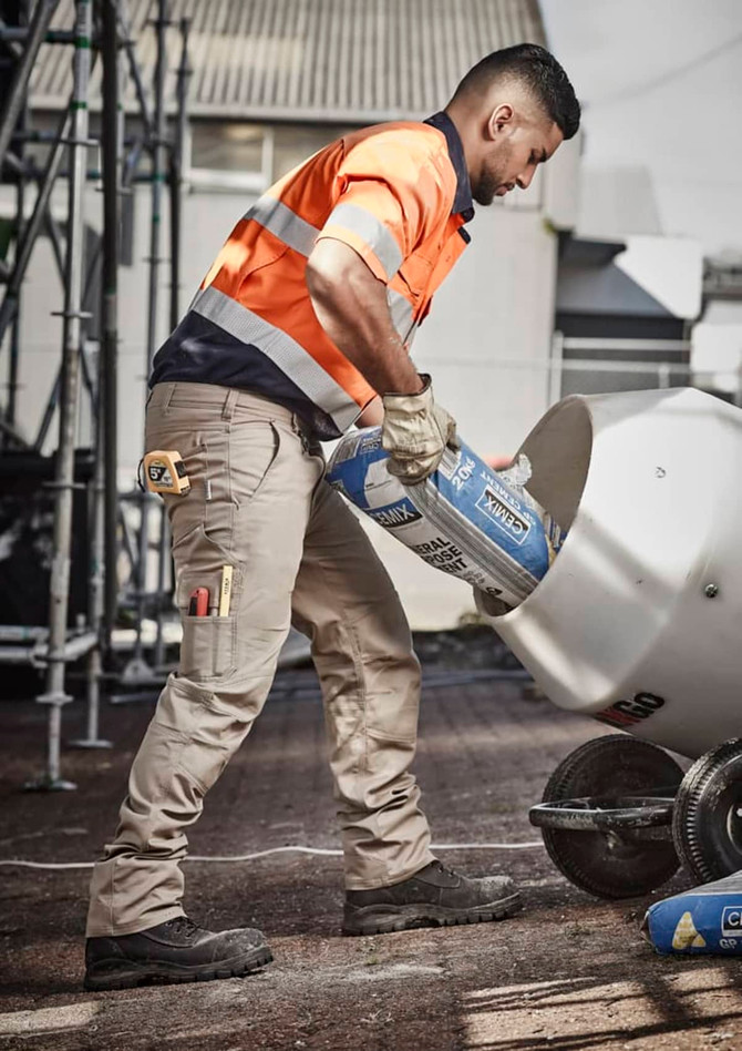 Men's rugged cooling cargo pants in khaki, featuring multiple pockets and a tool belt, worn by a worker on a construction site.