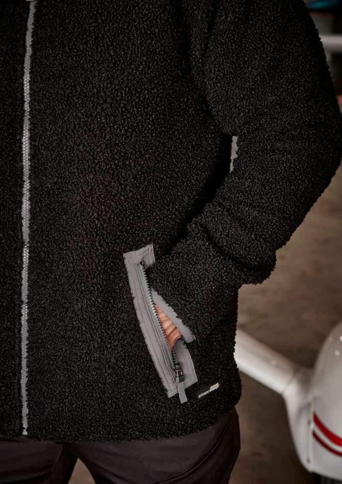 A black unisex full zip sherpa fleece jumper with side pockets and a logo.