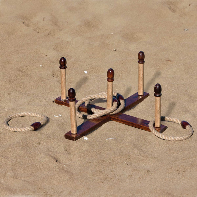A wooden backyard quoits set on sandy ground, featuring several pegs and rope rings. It has a natural wood finish.