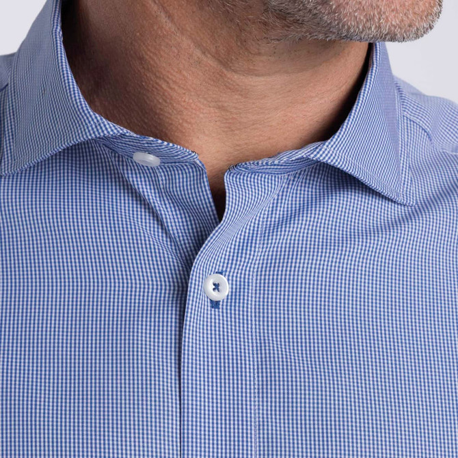A close-up of a men's button-up shirt featuring a blue check pattern and a collar with a logo.