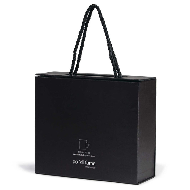 A black box with a handle, containing an espresso set, featuring a logo on the front.