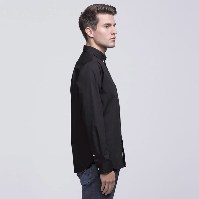 A side view of a black button-up shirt, featuring a collar and long sleeves, modelled by a man.