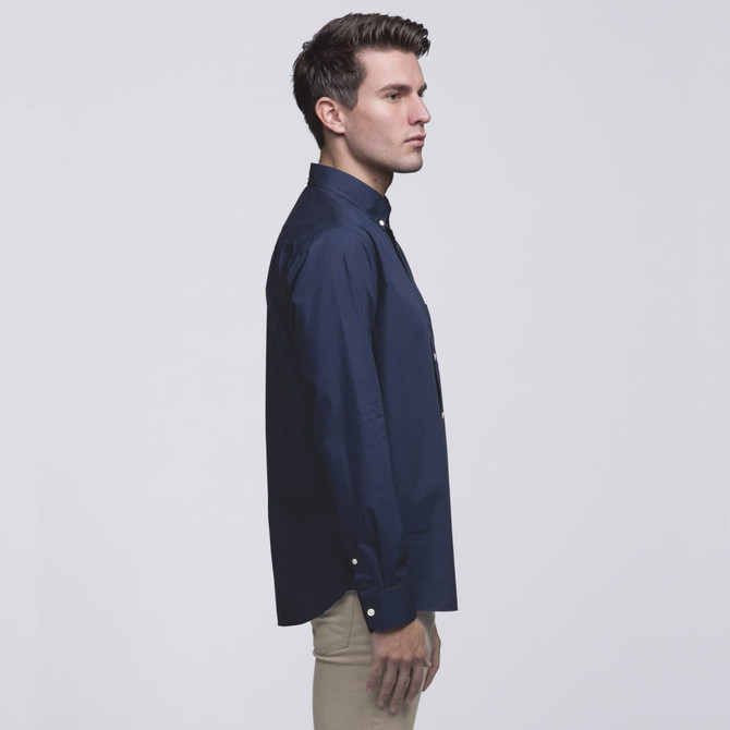 A navy button-up shirt displayed on a model from the side, featuring a collar and a logo.