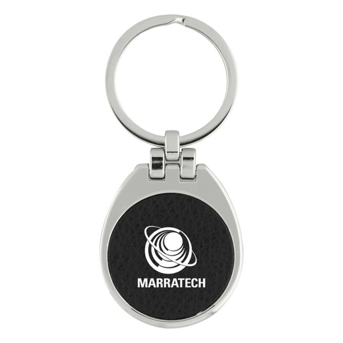 A keychain with a silver metallic finish and a black textured circular centre featuring a logo.