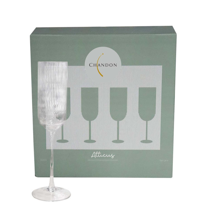A clear glass champagne flute with a ribbed texture, displayed in front of its green packaging featuring an emblem.