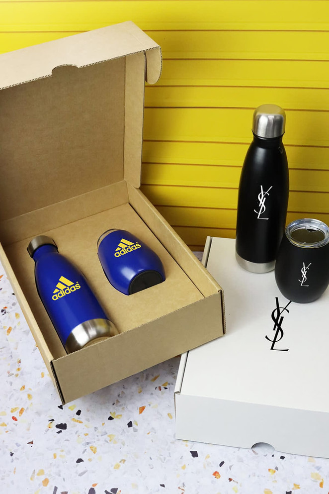A drink bottle set featuring a blue metallic bottle, a black bottle, and a glass tumbler, all in packaging with logos.