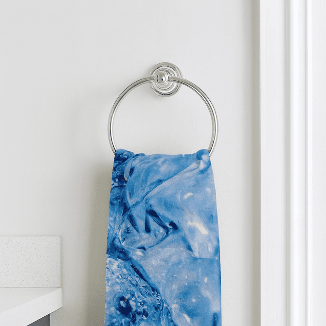 A blue marble-patterned hand towel hanging on a silver towel ring against a white wall.