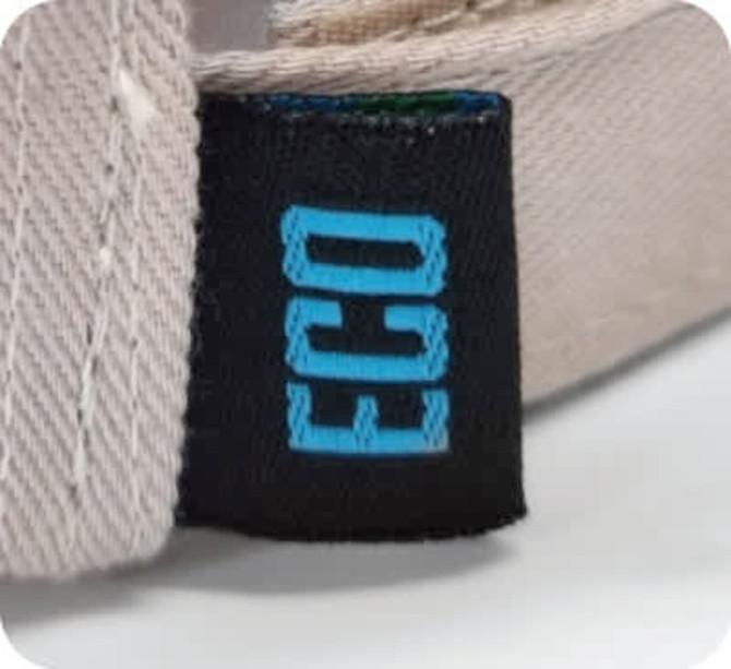 A close-up of a beige cap featuring a small black tag with a blue logo, indicating it is eco-friendly.