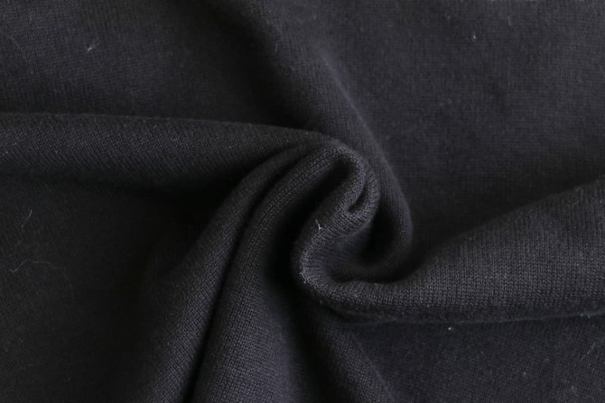 A close-up view of black 100% cotton fabric, showcasing its soft and textured surface.