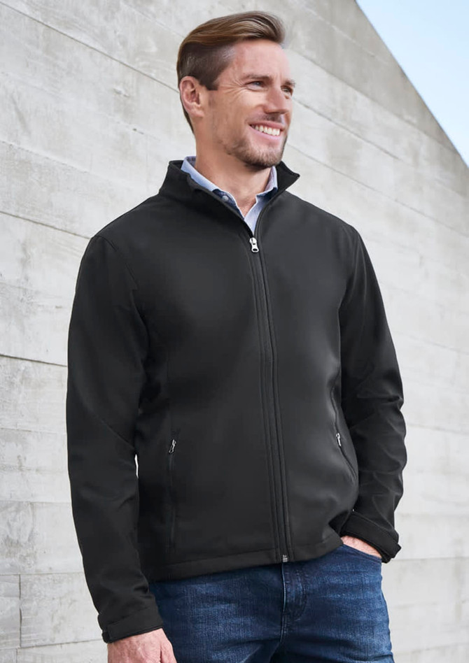 A black soft shell jacket featuring a zip front and side pockets, worn by a smiling man against a textured background.