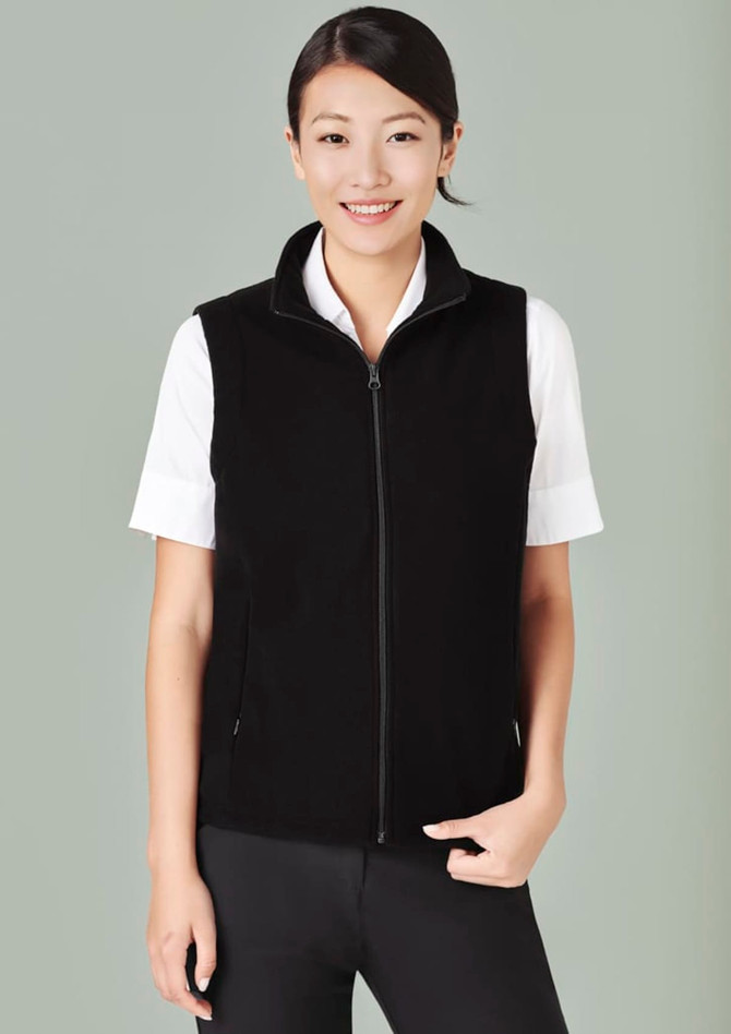 A black micro fleece vest with a zip, worn over a white shirt, featuring side pockets and a neckline zip.