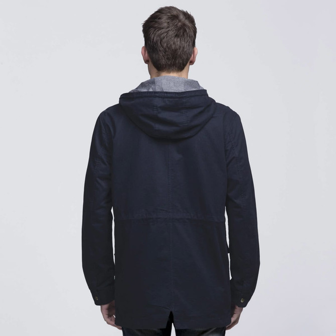 A navy blue twill jacket with a grey hood, featuring a logo. View from the back with a relaxed fit.
