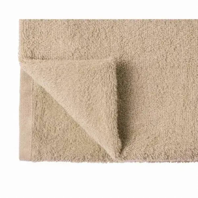A bath towel in organic cotton, featuring a soft, beige texture and a folded corner. Includes a logo.