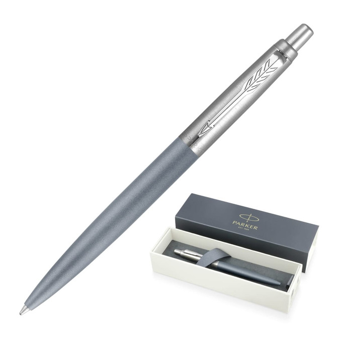 A ballpoint pen in matte grey, presented in a white box with a brand logo. The pen features sleek silver detailing.