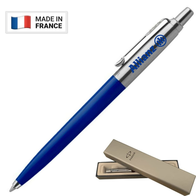A blue ballpoint pen with a metallic clip and branding, presented in a beige box. It has a logo and a "Made in France" tag.