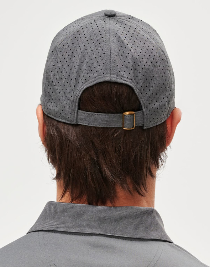 A grey cap with a laser cut design, featuring a rear adjustable strap and a logo.