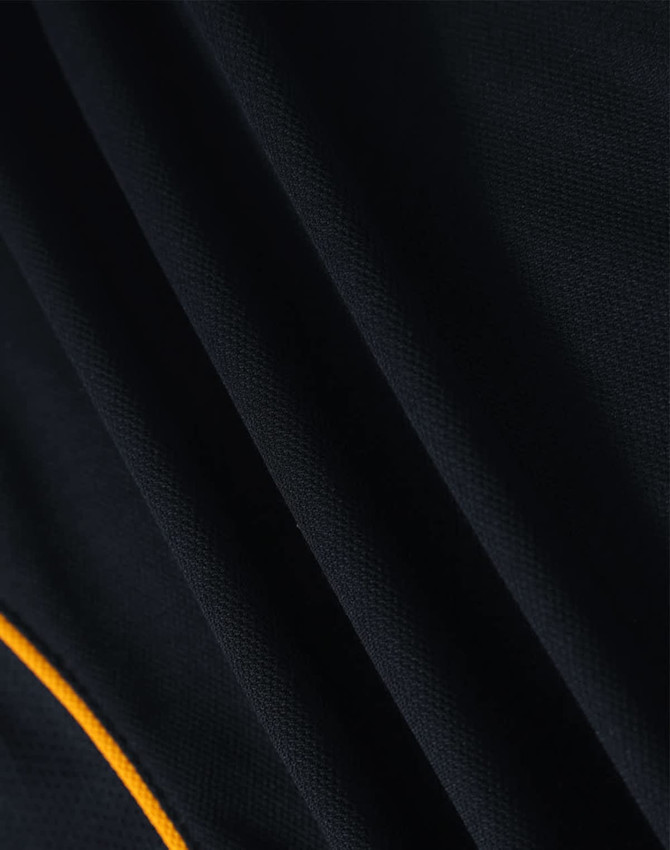 A close-up view of a black polo shirt featuring a contrasting yellow trim and textured fabric.