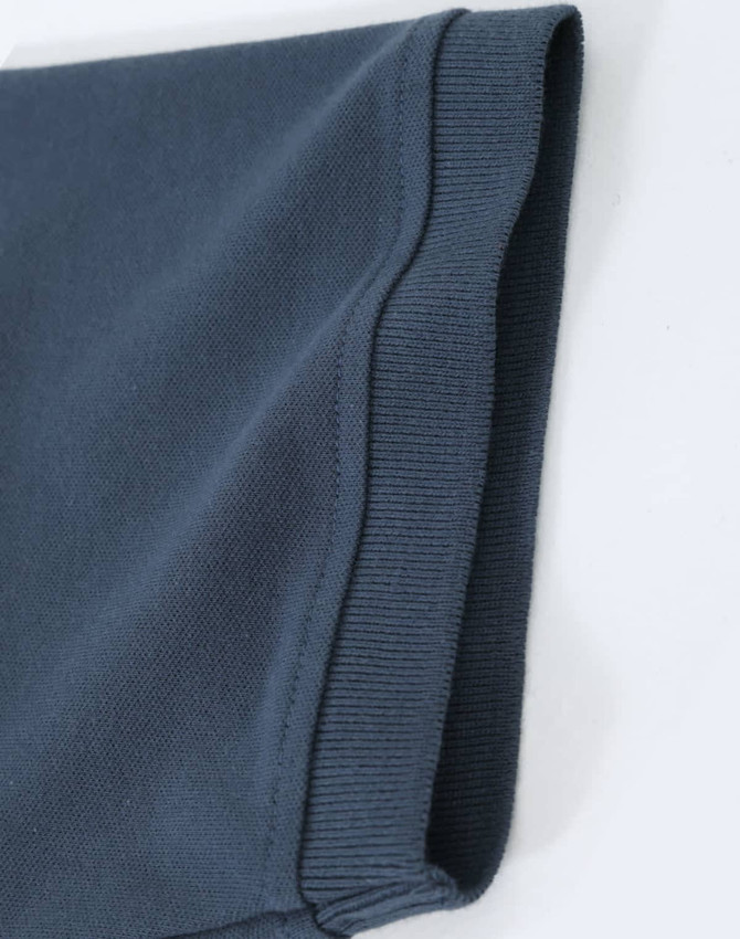 A close-up of a navy blue men's cotton stretch polo shirt, highlighting the fabric and sleeve detail.