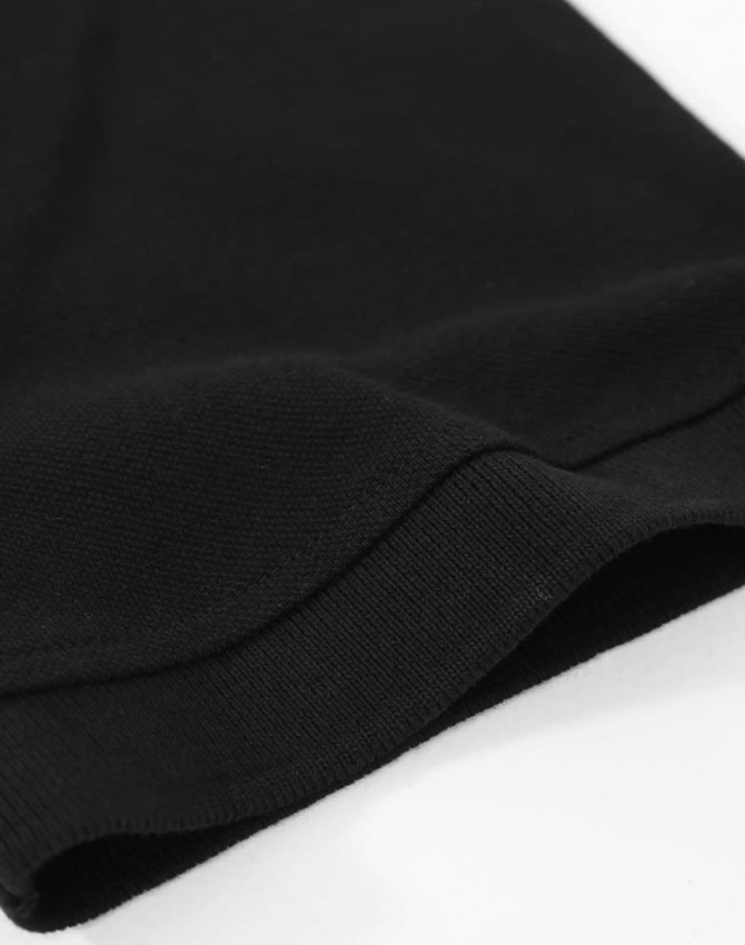 A black cotton stretch polo shirt featuring a close-up of the hem and sleeve detail, with a brand logo visible.
