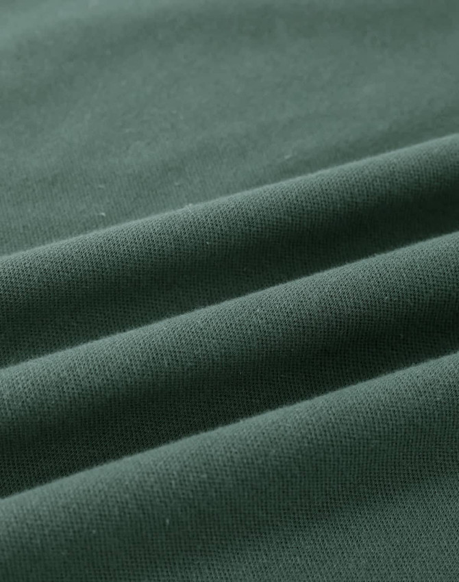 A close-up of a folded green cotton fabric, showcasing its soft texture and stretchability.