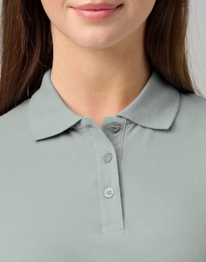 A close-up of a woman's light grey cotton stretch polo shirt with a collared neck and three buttons.