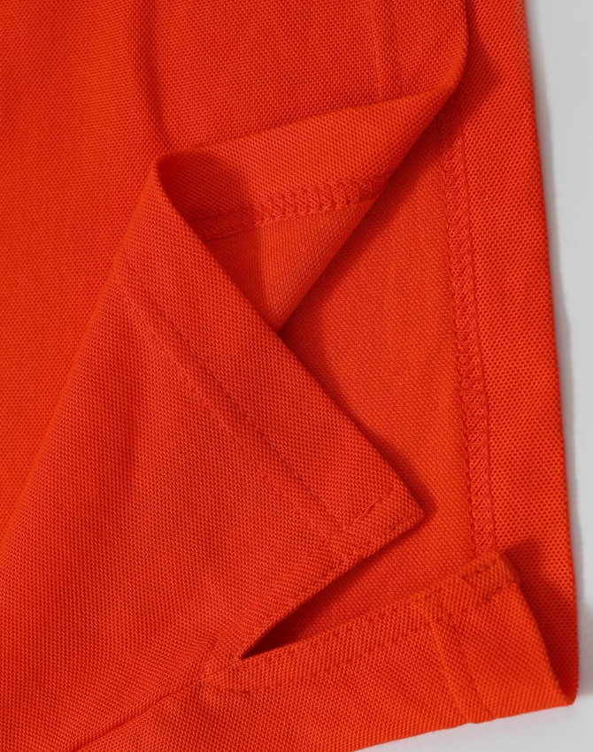 An orange Men's Truedry Pique Polo shirt, highlighting the fabric texture and seams. It features a logo.
