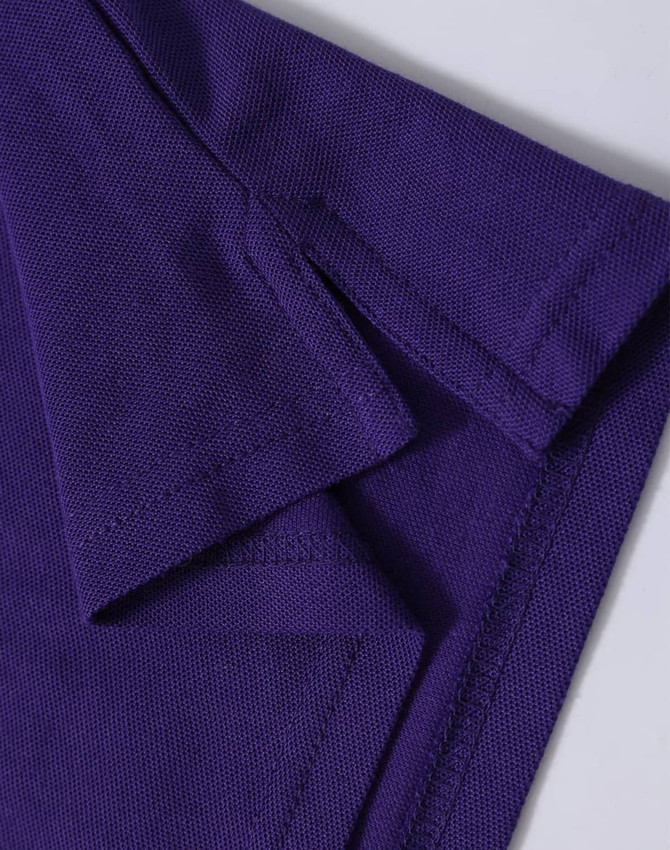 A close-up of a purple polo shirt, featuring a textured fabric and folded collar. The shirt has a logo.