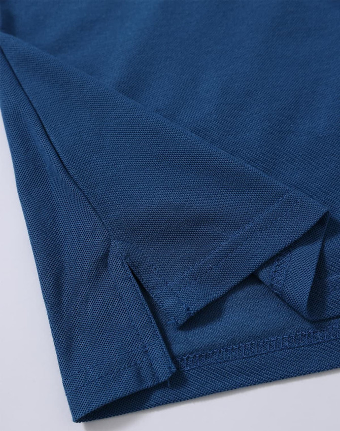 A close-up of a dark blue polo shirt featuring a folded hem and sleeve detail. The shirt has a subtle texture and branding.