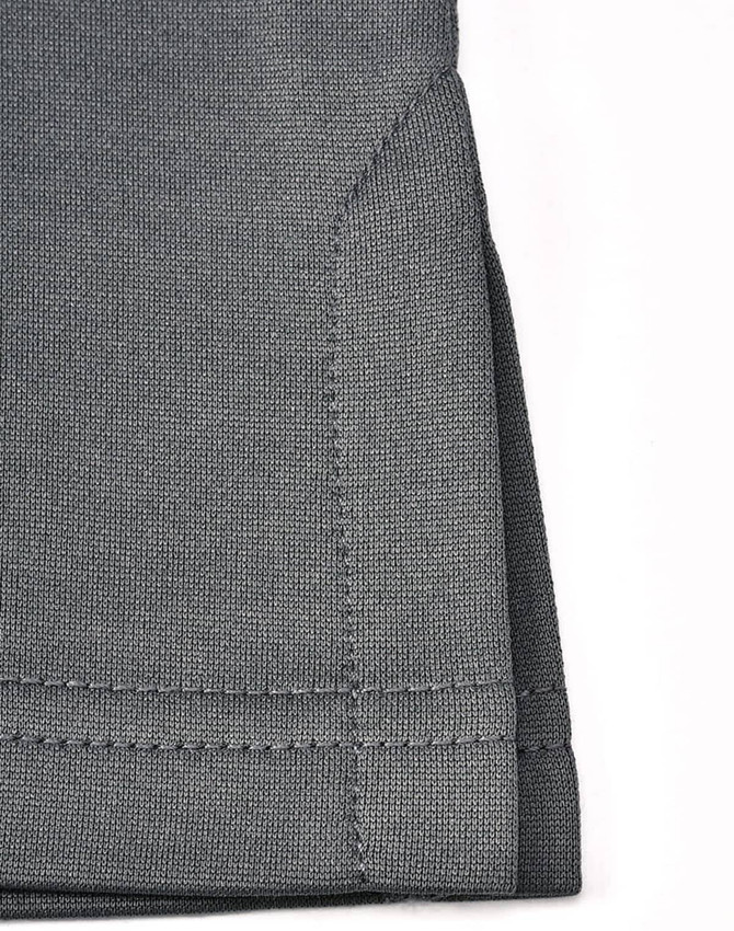 A close-up of the hem of a grey sustainable poly/cotton polo shirt featuring neat stitching and a folded edge.