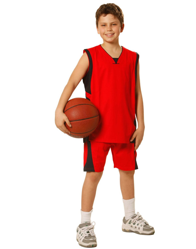 A young boy wearing red basketball shorts and a matching jersey, holding a basketball. The outfit has a logo.