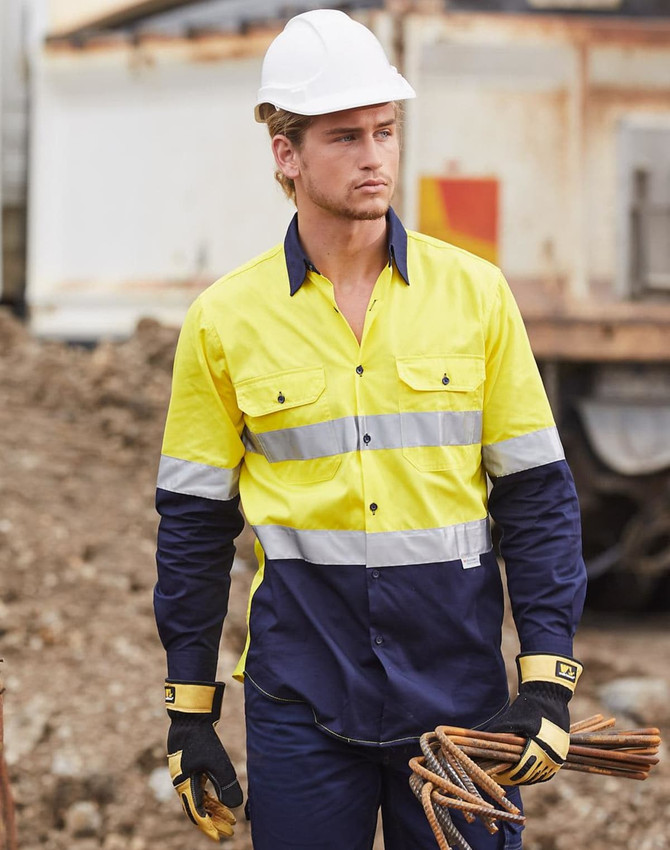 A high-visibility cotton drill shirt in yellow and navy with reflective stripes, worn by a model on a construction site.