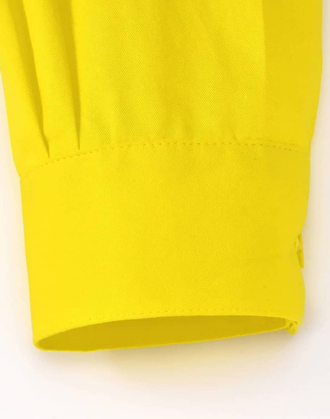 A close-up of a yellow long-sleeved shirt sleeve cuff, featuring a smooth fabric and a logo.