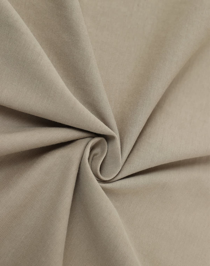 A close-up of beige premium cotton fabric, showcasing a smooth texture and soft, folded appearance.