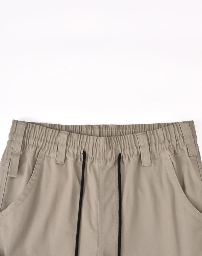 Pair of unisex cotton stretch drill work pants in a beige colour with an elasticised waistband and drawstring detail.