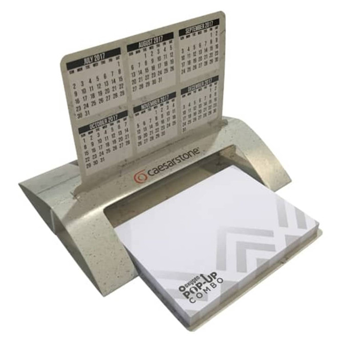 A desk calendar and notepad holder in grey with a logo, featuring monthly calendars above the notepad.