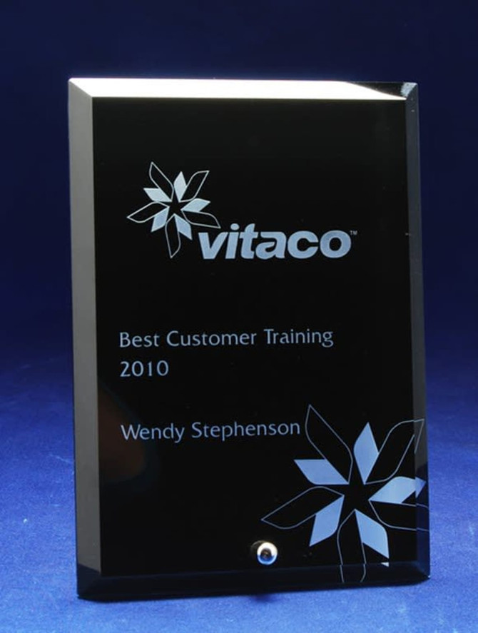 A glass rectangle award in black with a floral design and engraved text. It features a small silver embellishment.