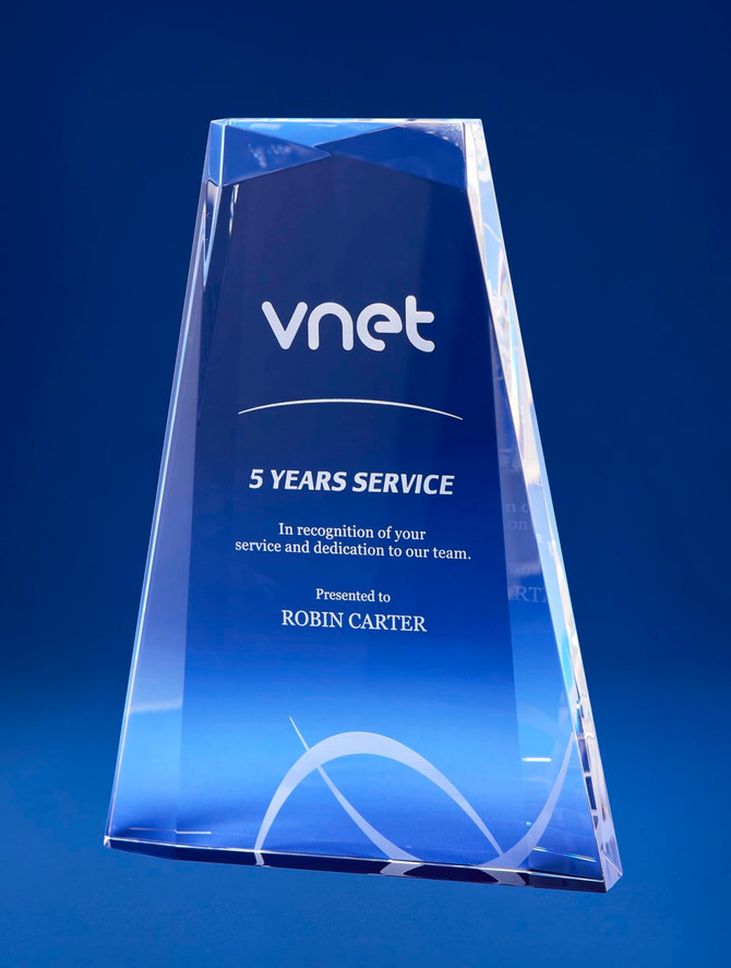 A crystal award with a multi-faceted design in clear and blue, featuring a logo and engraved text.