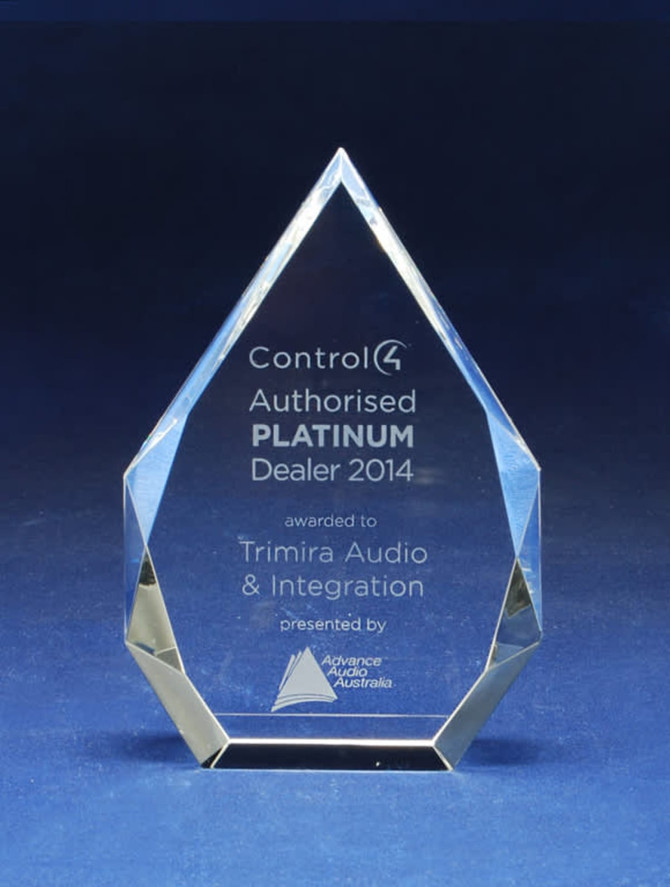 A crystal trophy with a pointed design, featuring engraved text and a rectangular base.