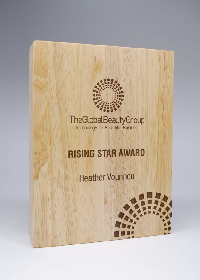 A wooden block award with engraved text and a logo, showcasing a light timber finish.
