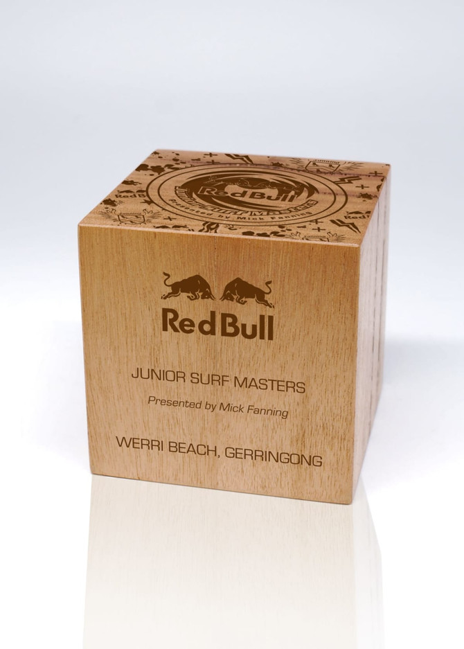 A wooden cube trophy with engraved details and a logo, featuring a natural finish.