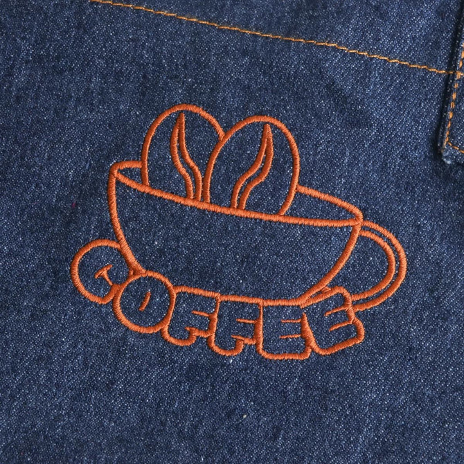 A denim apron featuring an orange embroidered design of a coffee cup with coffee beans.
