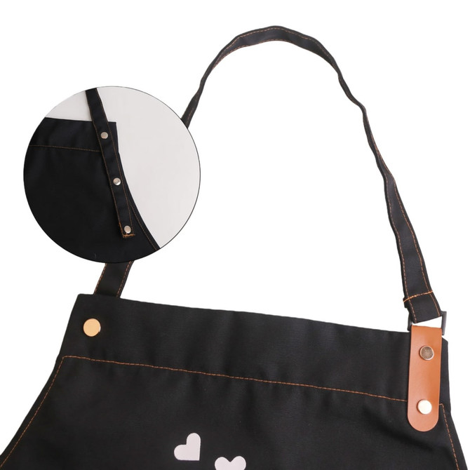 A black poly-cotton canvas full bib apron featuring a neck strap and snap buttons, with a logo on the front.