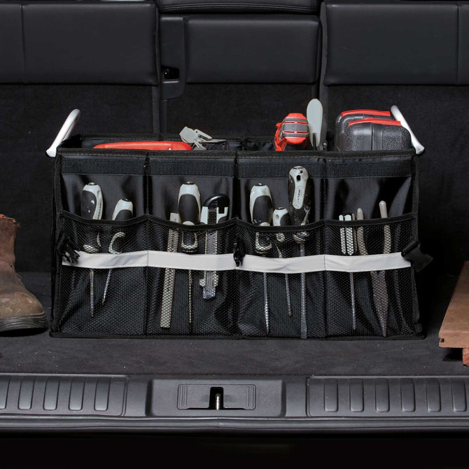 A black mesh organiser with multiple compartments filled with various tools, placed in a vehicle's boot.