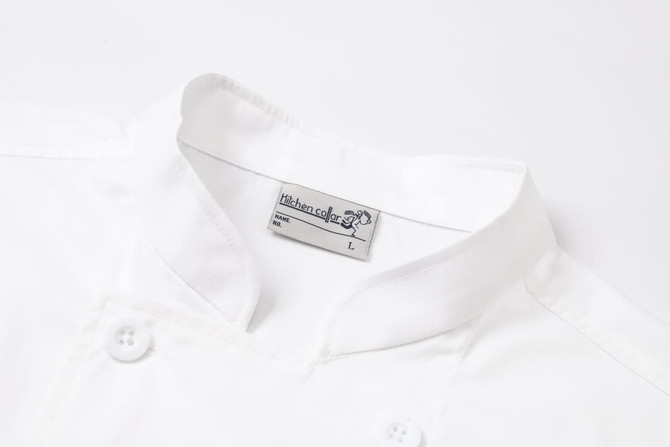 A white double-breasted chef jacket with short sleeves and a branded label near the collar.