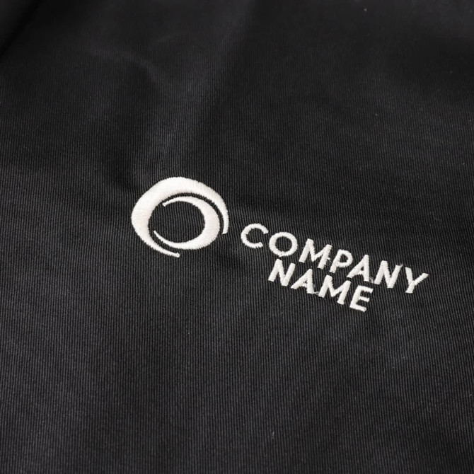 A black chef jacket featuring a single-breasted design and three-quarter sleeves, with an embroidered logo.