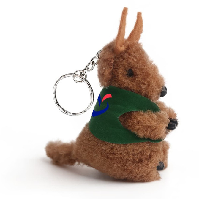 A brown kangaroo plush toy keychain with a green vest and a chain attachment. It has a logo on the vest.