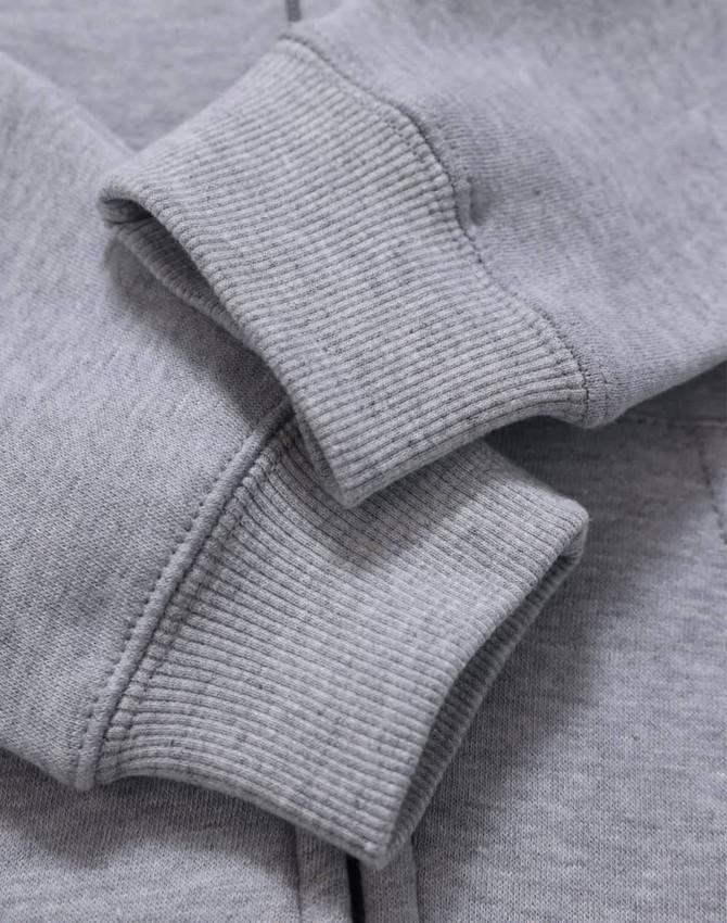 A grey full-zip fleecy hoodie featuring ribbed cuffs, highlighting texture and fabric detail. It has a logo.