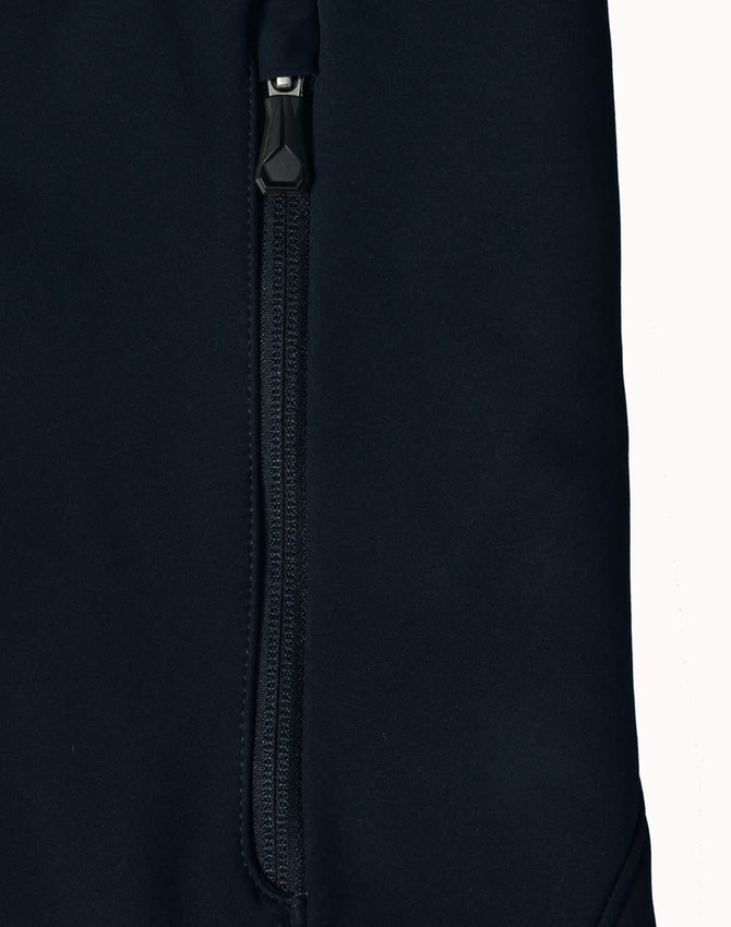 A dark navy softshell jacket featuring a zippered pocket and a sleek design. The jacket also has a logo.